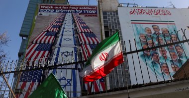 A billboard with anti-U.S. and anti-Israeli message is displayed on a building with a Iranian flag fluttering in front of it on a street in Tehran, Iran, Jan. 31, 2026. (Reuters Photo)