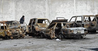 A man walks past burnt vehicles in a torched police station on the outskirts of Quetta, Pakistan, Feb. 1, 2026. (AFP Photo)