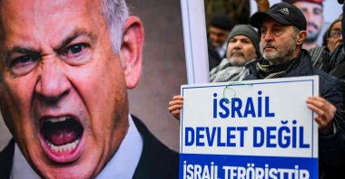 A protester holds a placard reading "Israel is not a state, Israel is a terrorist state” near a poster of Israeli Prime Minister Benjamin Netanyahu during an anti-USA demonstration in front of the U.S. consulate in Istanbul, Türkiye, Feb. 1, 2026. (AFP Photo)