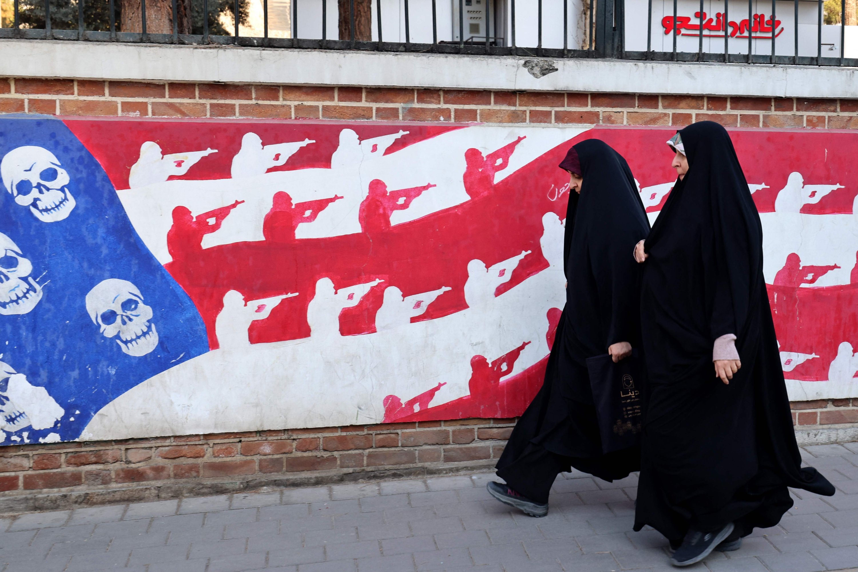 Women walk past a mural painted on the outer walls of the former U.S. Embassy, Tehran, Iran, Feb. 1, 2026. (AFP Photo)