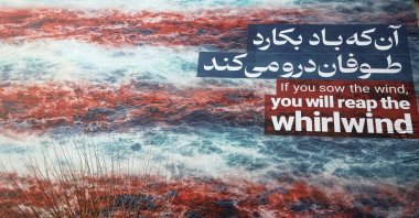 In a giant poster featuring an image of the American flag in blood targeting an American aircraft carrier, the phrase “He who sows the wind shall reap the whirlwind” appears in English and Persian, Revolution Square, Tehran, Iran, Jan. 25, 2026. (AA Photo)