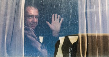 A Palestinian man waves from a window as war-wounded people, accompanied by relatives, get ready to leave Gaza through the Rafah border crossing between Gaza and Egypt, in Khan Younis in the southern Gaza Strip, Feb. 3, 2026. (Reuters Photo)