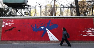 A woman walks past a mural depicting a U.S. drone painted on the outer walls of the former U.S. embassy in Tehran, Iran, Feb. 1, 2026. (AFP Photo)