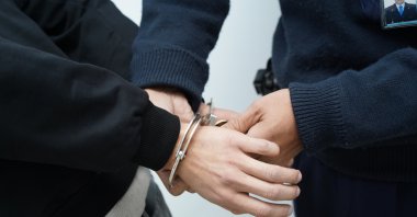 A young suspect is handcuffed by police during an operation targeting organized crime. (Shutterstcok Photo)