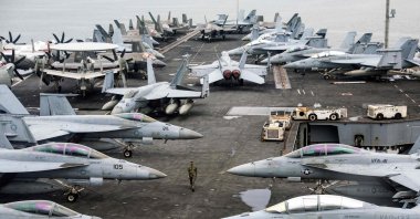 A U.S. Navy officer walks past fighter jets sitting on the flight deck of the Nimitz-class aircraft carrier USS Abraham Lincoln during a media tour in Port Klang, on the outskirts of Kuala Lumpur, Nov. 26, 2024. (AFP File Photo)