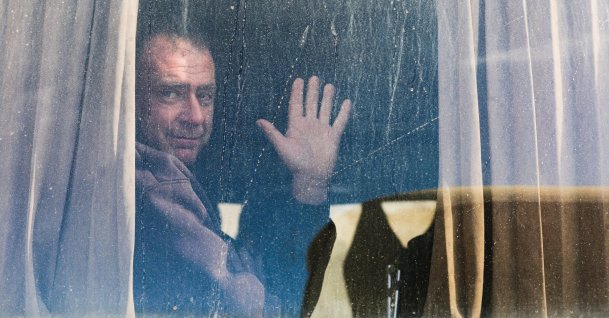 A Palestinian man waves from a window as war-wounded people, accompanied by relatives, get ready to leave Gaza through the Rafah border crossing between Gaza and Egypt, in Khan Younis in the southern Gaza Strip, Feb. 3, 2026. (Reuters Photo)