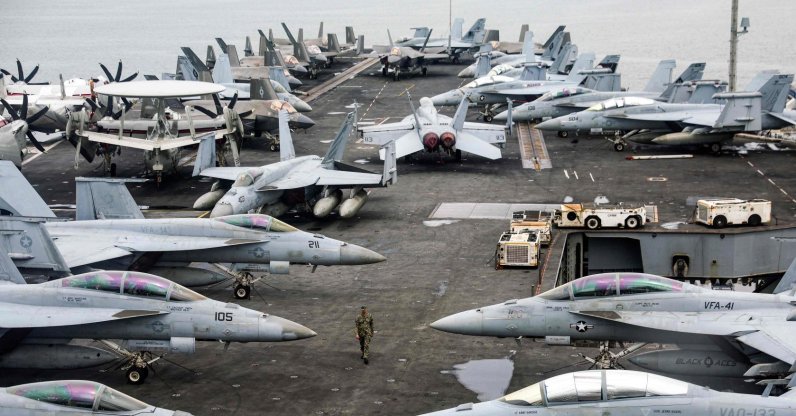 A U.S. Navy officer walks past fighter jets sitting on the flight deck of the Nimitz-class aircraft carrier USS Abraham Lincoln during a media tour in Port Klang, on the outskirts of Kuala Lumpur, Nov. 26, 2024. (AFP File Photo)