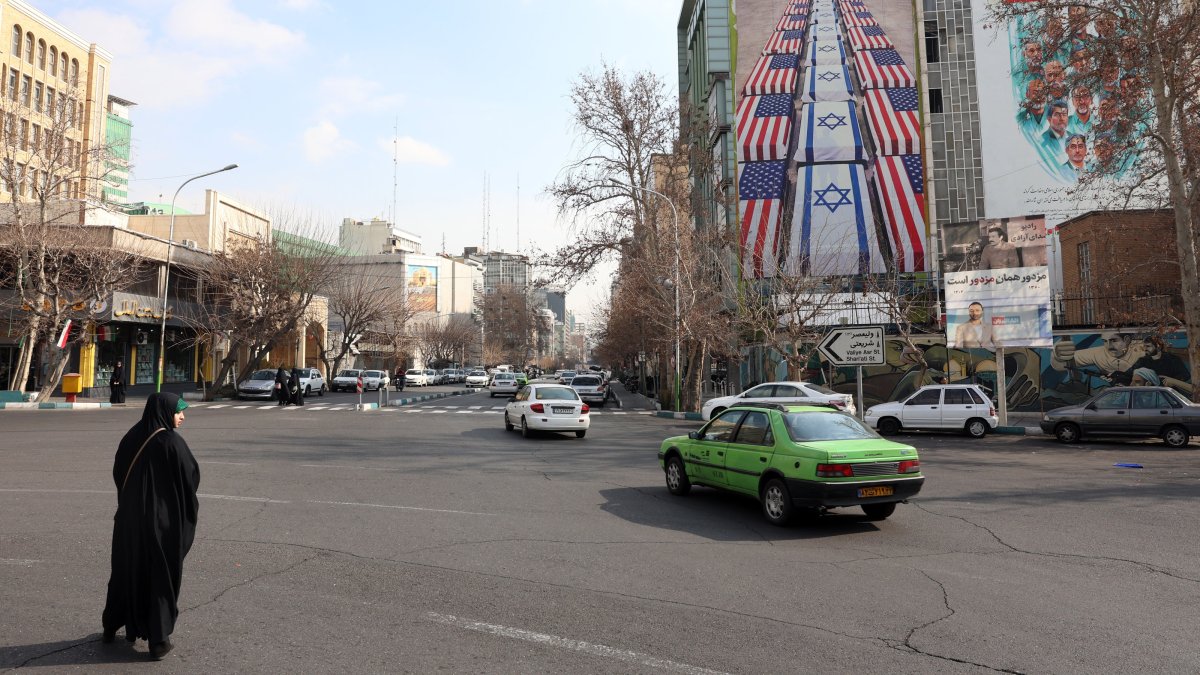Iranians drive near an anti-U.S. and Israel billboard in Tehran, Iran, Jan. 29, 2026. (EPA Photo)