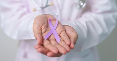 A doctor holds a purple ribbon to mark World Cancer Day. (Shutterstock Photo)