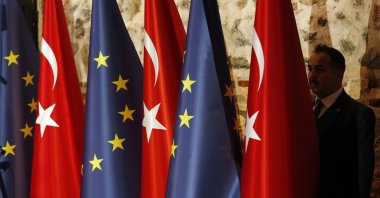 An official adjusts Turkish and European flags prior to the opening session of a high-level meeting, Istanbul, Türkiye, Feb.28, 2019. (AP Photo)