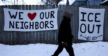 A man walks past signs hanging on a fence in Minneapolis, Minnesota, U.S., Feb. 3, 2026. (AFP Photo)