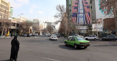Iranians drive near an anti-U.S. and Israel billboard in Tehran, Iran, Jan. 29, 2026. (EPA Photo)