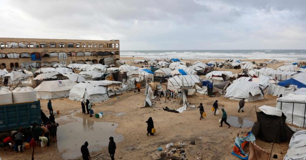 Displaced Palestinians carry jerricans amid tent shelters set up along the shore in Gaza City as strong winter winds sweep the Palestinian enclave, Jan. 13, 2026. (AFP Photo)