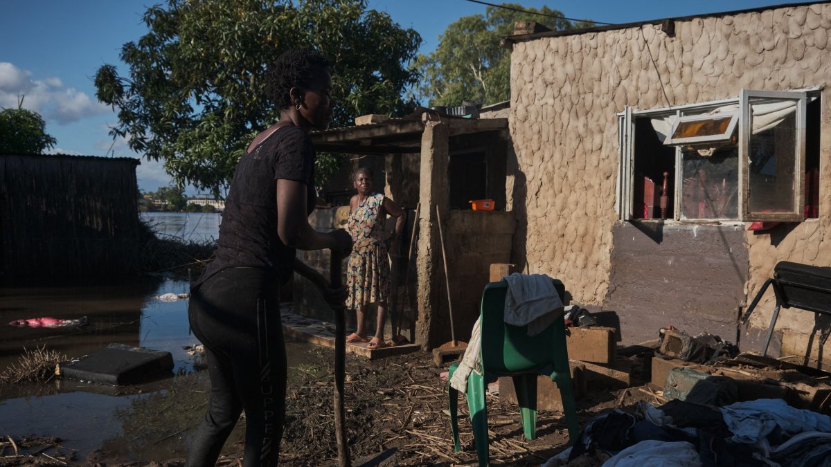 A family clears debris in a yard submerged in flood water from the nearby Limpopo river, Xai Xai, Gaza Province, Mozambique, Feb. 5, 2025. (AFP Photo)
