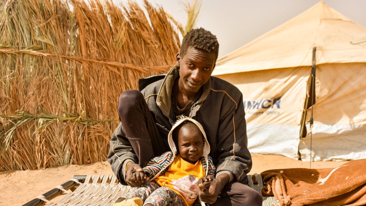 A displaced Sudanese father sits with his young child on a makeshift bed at El-Affad Refugee Camp, Ed-Debbe, Sudan, Jan. 13, 2026. (AA Photo)