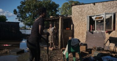A family clears debris in a yard submerged in flood water from the nearby Limpopo river, Xai Xai, Gaza Province, Mozambique, Feb. 5, 2025. (AFP Photo)