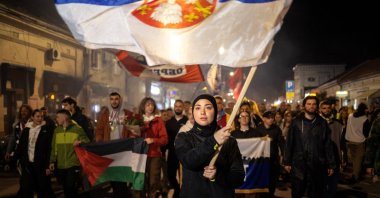Student Merima Avdic from Novi Pazar waves a Serbian flag as they are welcomed by locals on their journey to Novi Sad, during a protest march over the fatal November 2024 Novi Sad railway station canopy collapse, which killed 16 people triggering nationwide accusations of widespread corruption and negligence, Obrenovac, Serbia, Oct. 27, 2025. (Reuters Photo)