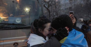Olha Kurtmallaieva (L) hugs her husband Ruslan draped in a Ukrainian national flag, a released prisoner of war (POW) who was captured during the defense of Mariupol in 2022, upon his arrival after a prisoner exchange in the Chernihiv region, Ukraine, Feb. 5, 2026. (AFP Photo)
