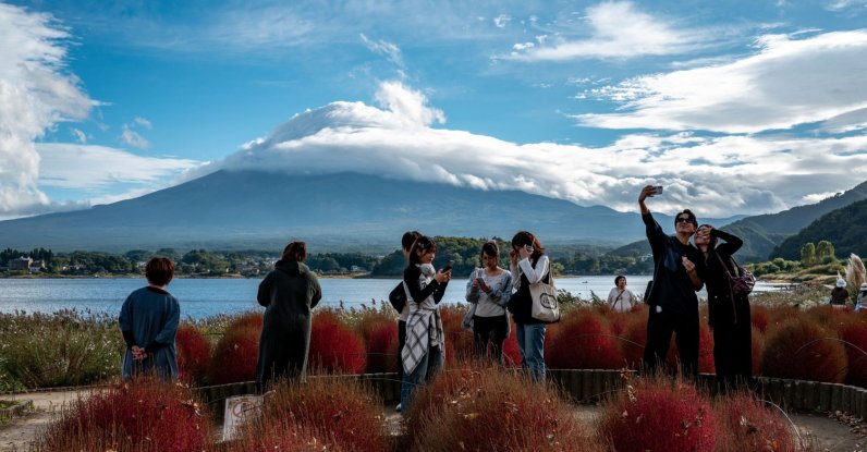 Tourists take pictures as cloud-clad Mount Fuji is seen in the background from Oishi park in the town of Fujikawaguchiko, Yamanashi Prefecture, Japan, Oct. 18, 2025. (AFP Photo)