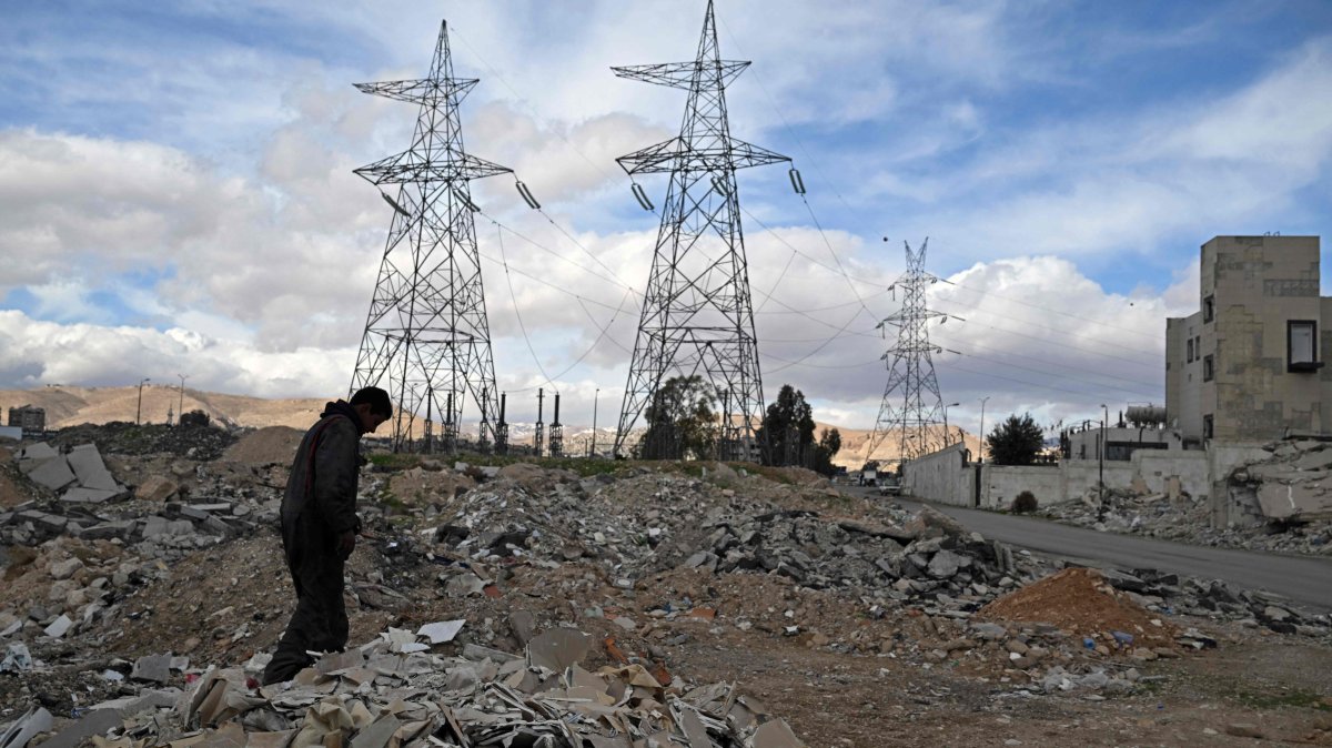 A man walks amid rubble of buildings against the backdrop of electric pylons near Damascus, Syria, Jan. 29, 2026. (AFP Photo)