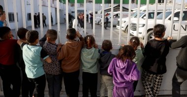 Palestinian children watch as war-wounded Palestinians and other patients prepare to leave the Gaza Strip for treatment through the Rafah border crossing, in Khan Younis, southern Gaza Strip, Feb. 8, 2026. (AFP Photo)