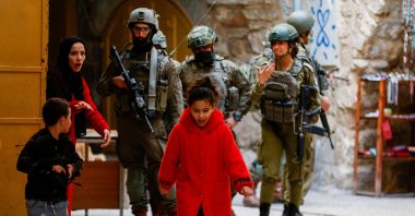 A Palestinian woman ushers her children away from a group of Israeli soldiers during a weekly settlers’ tour in Hebron, in the Israeli‑occupied West Bank, Jan. 24, 2026. (Reuters Photo)