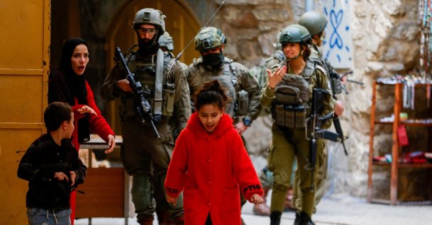 A Palestinian woman ushers her children away from a group of Israeli soldiers during a weekly settlers’ tour in Hebron, in the Israeli‑occupied West Bank, Jan. 24, 2026. (Reuters Photo)