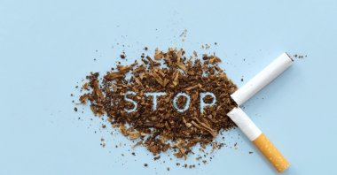 Broken cigarette and scattered tobacco with the word "STOP" on a light blue background. (Shutterstock Photo)