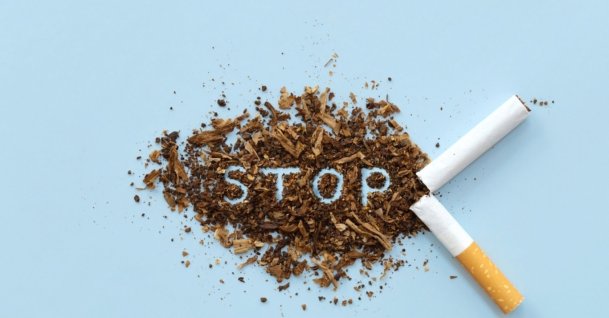 Broken cigarette and scattered tobacco with the word "STOP" on a light blue background. (Shutterstock Photo)