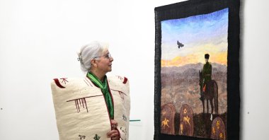 Felt artist Nur Sağlamer looks at her artwork on display at the "Aşina" exhibition at Galeri T in Antalya, southern Türkiye, Feb. 5, 2026. (AA Photo)