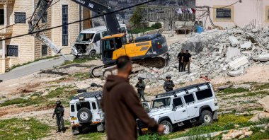 A demolition excavator used by Israeli security forces demolishes a building in the Palestinian village of Beit Awa in the southwest of the occupied West Bank, Feb. 11, 2026. (AFP Photo)