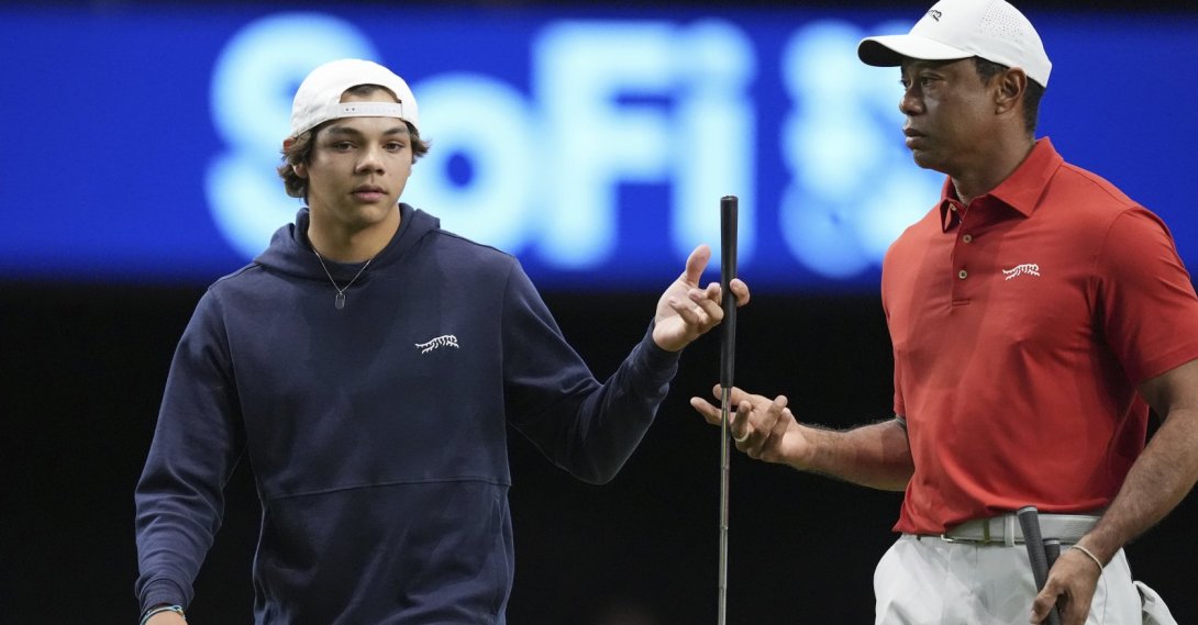 Charlie Woods (L) hands a club to his father, Tiger Woods, during warm-ups for a match as part of the TMRW Golf League, Palm Beach Gardens, U.S., Jan. 27, 2025. (AP Photo)