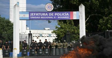 Members of the Infantry Police guard the entrance of the Santa Fe provincial police headquarters as a fire burns in front during a protest demanding higher salaries and improved mental health support for the force amid growing pressure from long working hours, in Rosario, Santa Fe Province, Argentina, Feb. 11, 2026. (AFP Photo)