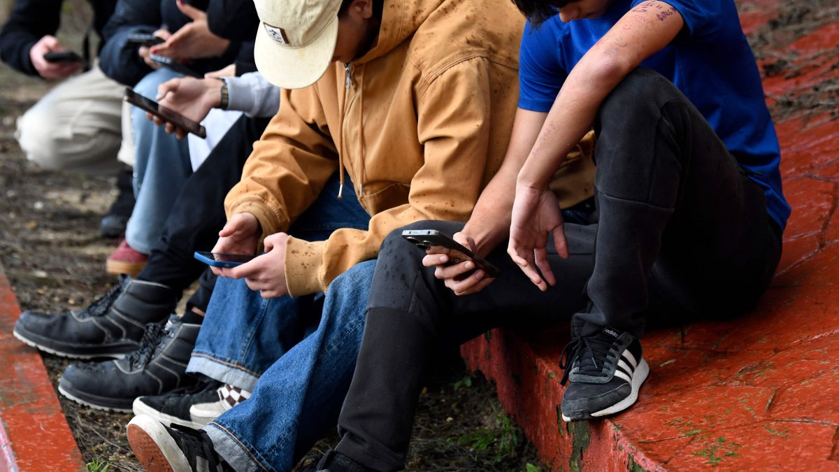 Teenagers use their smartphones at the entrance of their school in Tomares, Seville, Spain, Feb. 6, 2026. (AFP Photo)