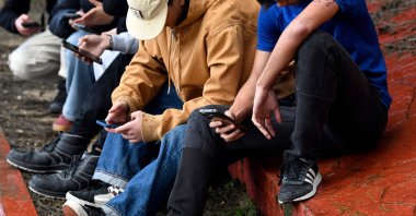 Teenagers use their smartphones at the entrance of their school in Tomares, Seville, Spain, Feb. 6, 2026. (AFP Photo)