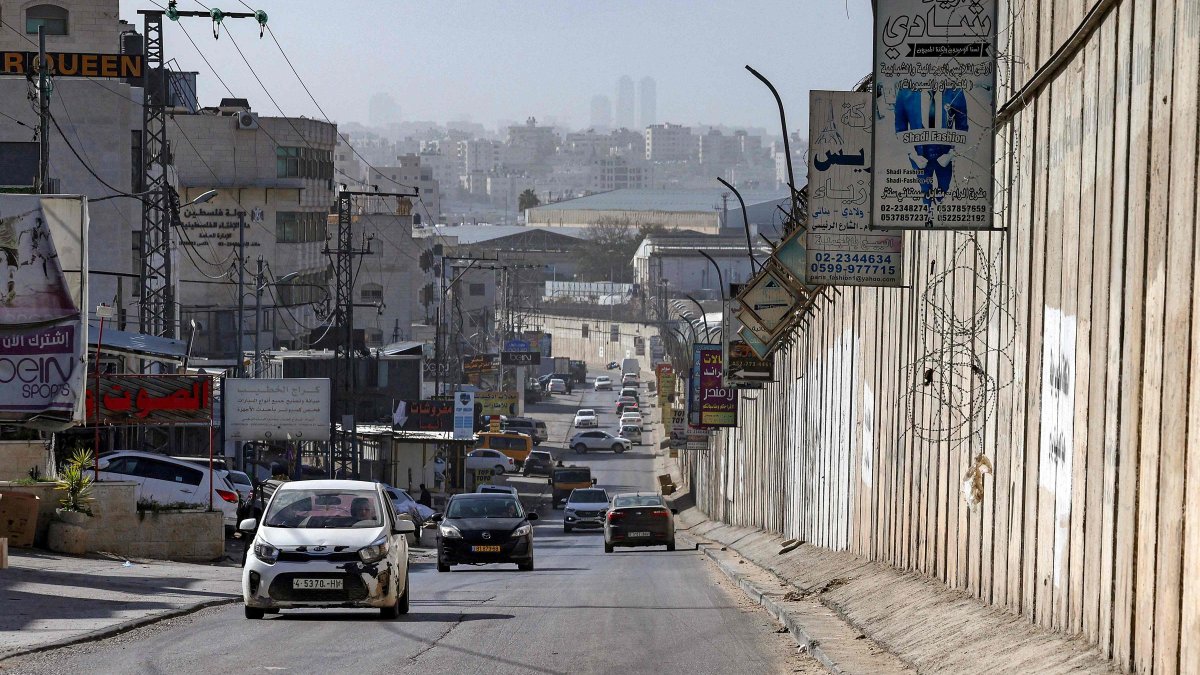Vehicles move along a road next to Israel's controversial separation barrier in the Palestinian village of al-Ram in the occupied West Bank, Feb. 16, 2026. (AFP Photo)