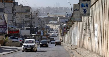 Vehicles move along a road next to Israel's controversial separation barrier in the Palestinian village of al-Ram in the occupied West Bank, Feb. 16, 2026. (AFP Photo)