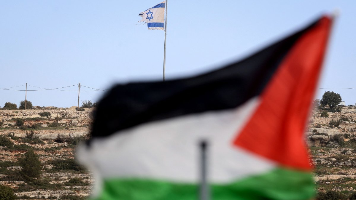 A Palestinian flag flutters with an Israeli flag in backgroud on a hilltop overlooking the village of Umm Safa, north of Ramallah, occupied West Bank, Palestine, Feb. 16, 2026.