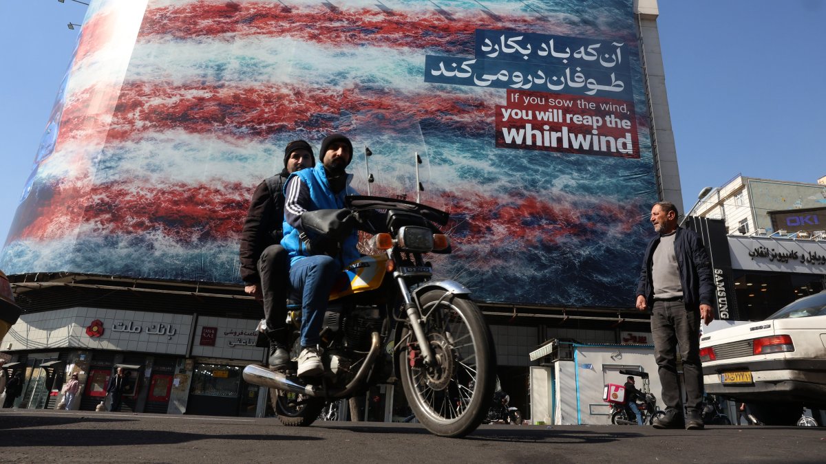 Iranians drive past an anti-U.S. billboard at Enqelab Square in Tehran, Iran, Feb. 16, 2026. (EPA Photo)