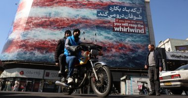 Iranians drive past an anti-U.S. billboard at Enqelab Square in Tehran, Iran, Feb. 16, 2026. (EPA Photo)