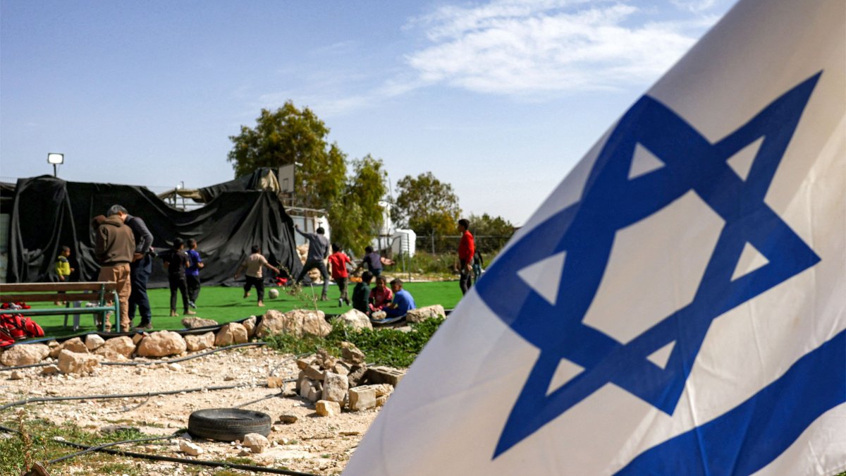 Palestinian boys play football on a pitch surrounded by Israeli flags, placed by Israeli settlers near a new outpost near the village of Umm al-Kheir, occupied West Bank, Palestine, Feb. 12, 2026. (AFP Photo)