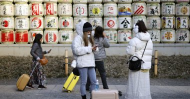 Tourists stroll past sake barrels displayed at the Meiji Jingu shrine, Tokyo, Japan, Jan. 21, 2026. (EPA Photo)