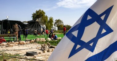 Palestinian boys play football on a pitch surrounded by Israeli flags, placed by Israeli settlers near a new outpost near the village of Umm al-Kheir, occupied West Bank, Palestine, Feb. 12, 2026. (AFP Photo)