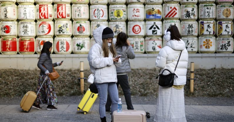 Tourists stroll past sake barrels displayed at the Meiji Jingu shrine, Tokyo, Japan, Jan. 21, 2026. (EPA Photo)