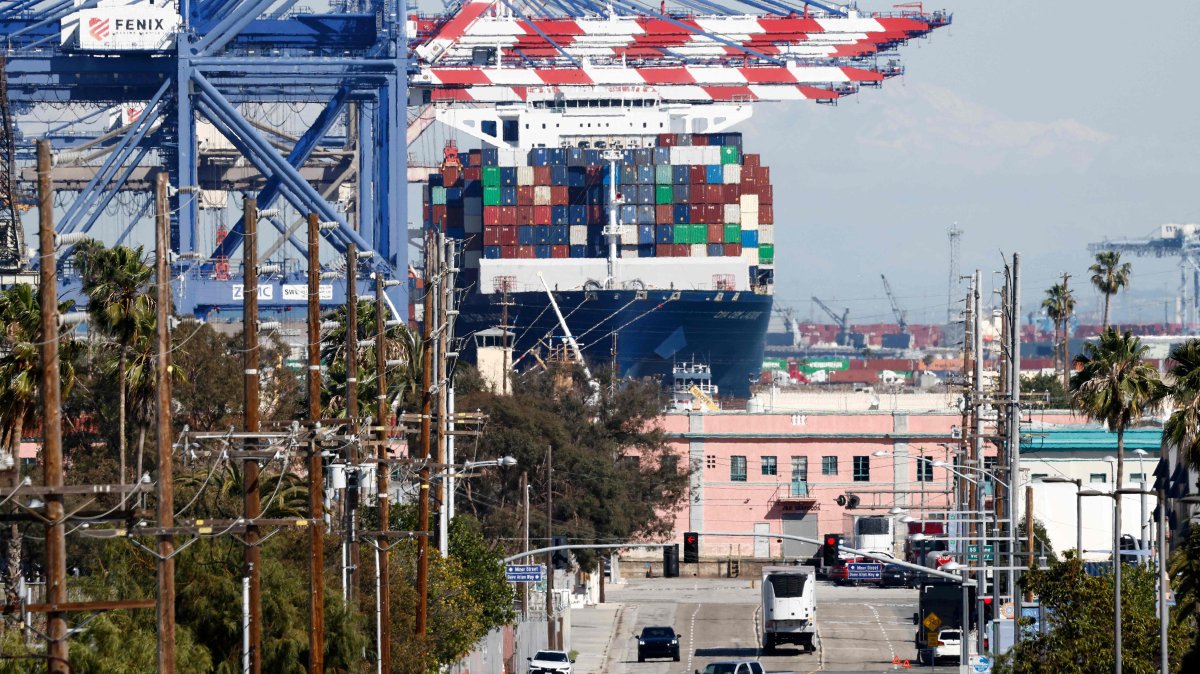 A container ship floats loaded with shipping containers at the Port of Los Angeles as vehicles drive nearby in Los Angeles, California, U.S., Feb. 20, 2026. (AFP Photo)