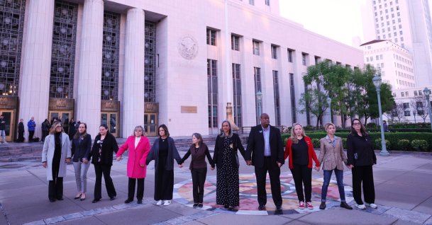 A group holds hands outside a landmark trial over whether social media platforms deliberately addict and harm children, in Los Angeles, U.S., Feb. 18, 2026. (AP Photo)