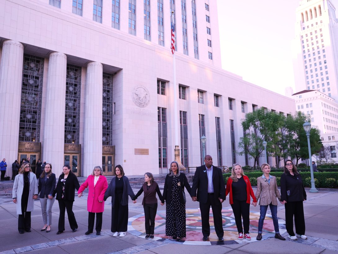 A group holds hands outside a landmark trial over whether social media platforms deliberately addict and harm children, in Los Angeles, U.S., Feb. 18, 2026. (AP Photo)