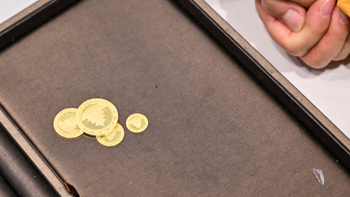 A woman waits to sell her gold next to a Smart Gold Store Machine placed in a shopping mall in Shanghai, China, Jan. 29, 2026. (AFP Photo)