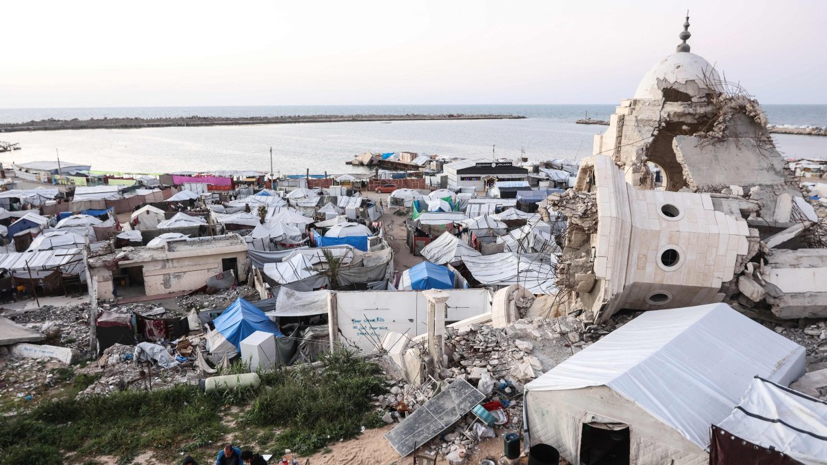 Members of the displaced Palestinian al-Ghafir family sit together to break their Ramadan fast during iftar beside their tent, erected amid the ruins of the al-Hasayna Mosque, Gaza City, Palestine, Feb. 21, 2026. (AFP Photo)
