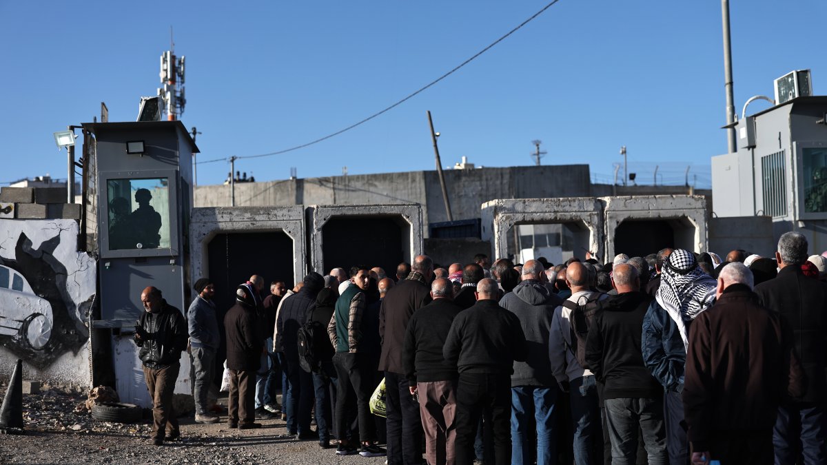 Israeli soldiers stand guard as Palestinians wait in line to cross at the Israeli checkpoint of Qalandia between the West Bank and Jerusalem, to attend the first Friday prayer of Ramadan in Al Aqsa Mosque in Jerusalem, Feb. 20, 2026. (EPA Photo)